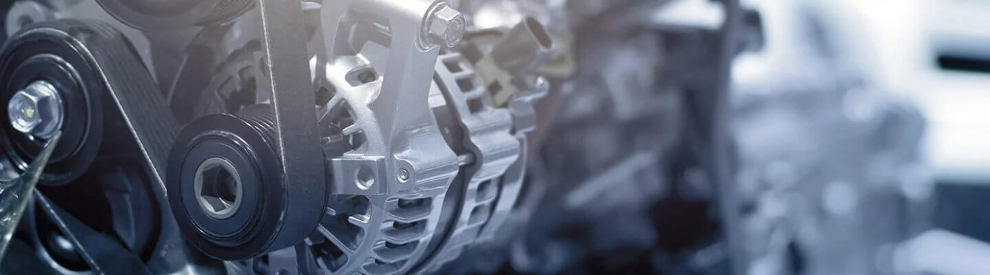 Close-up of a mechanical engine component, featuring metallic parts, gears, and belts. The image captures the intricate design and structure, highlighting the shiny surfaces and detailed engineering elements.