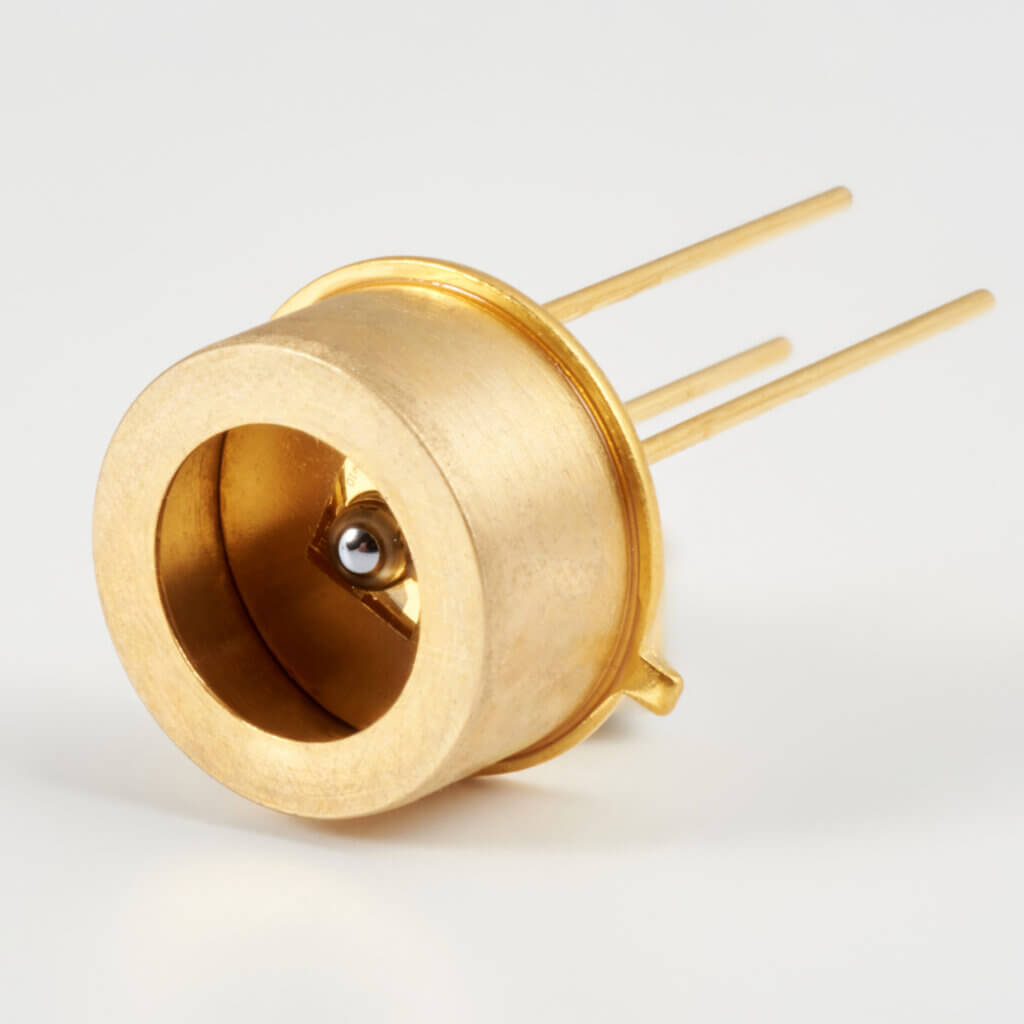A close-up of a gold-colored electronic component with three long pins, a cylindrical body, and a small sensor or diode in the center.