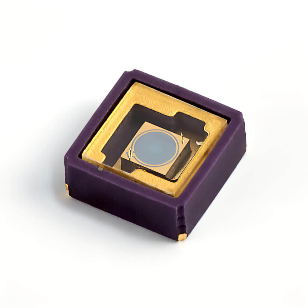 A close-up of a square electronic component with a purple and gold casing and a circular lens or sensor in the center, placed on a white background.