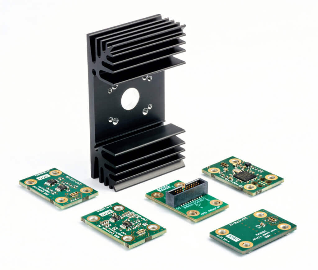 Five green circuit boards with various electronic components are arranged around a large black metal heatsink with fins, all displayed on a white background.