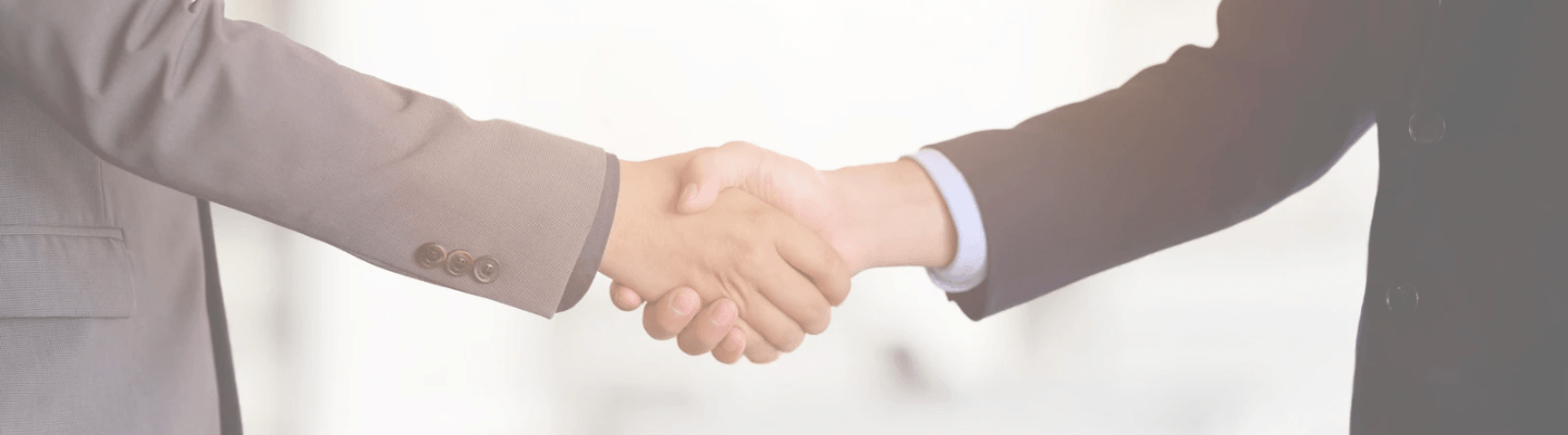 Two people in business suits shaking hands.