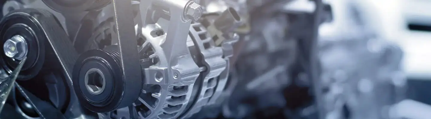Close-up of a mechanical engine component, featuring metallic parts, gears, and belts. The image captures the intricate design and structure, highlighting the shiny surfaces and detailed engineering elements.