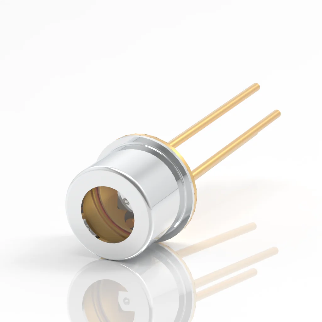 A small cylindrical laser diode with a metallic silver housing and two gold pins extending from one end, placed on a glossy white surface, reflecting its image.